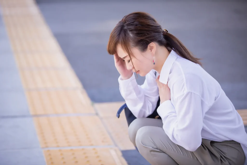 頭を押さえて座り込む女性