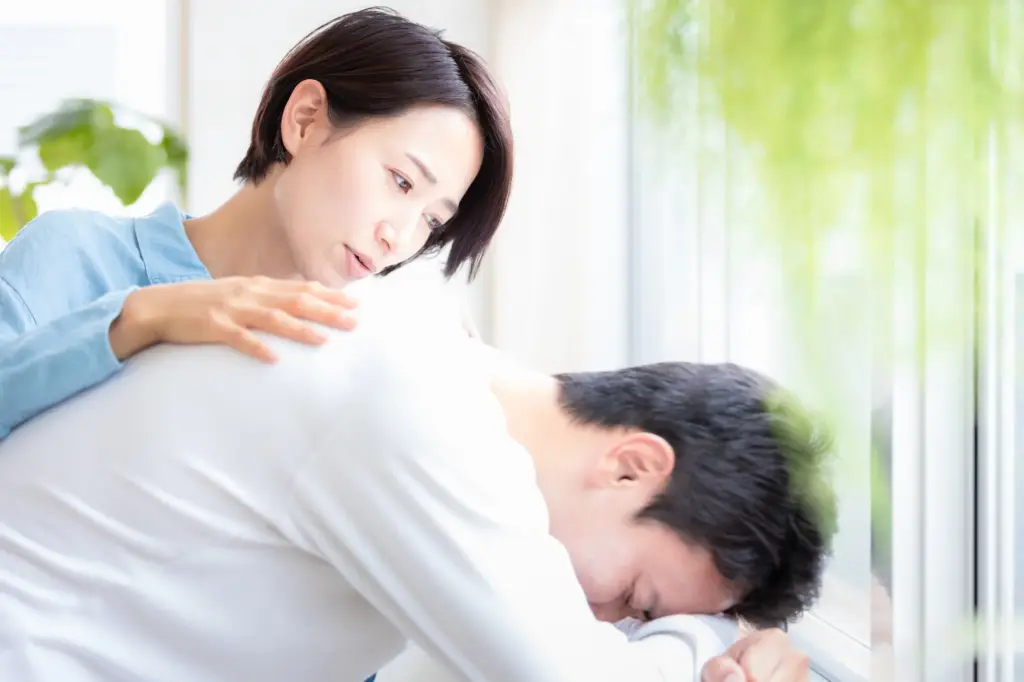 男性の背中をさする女性